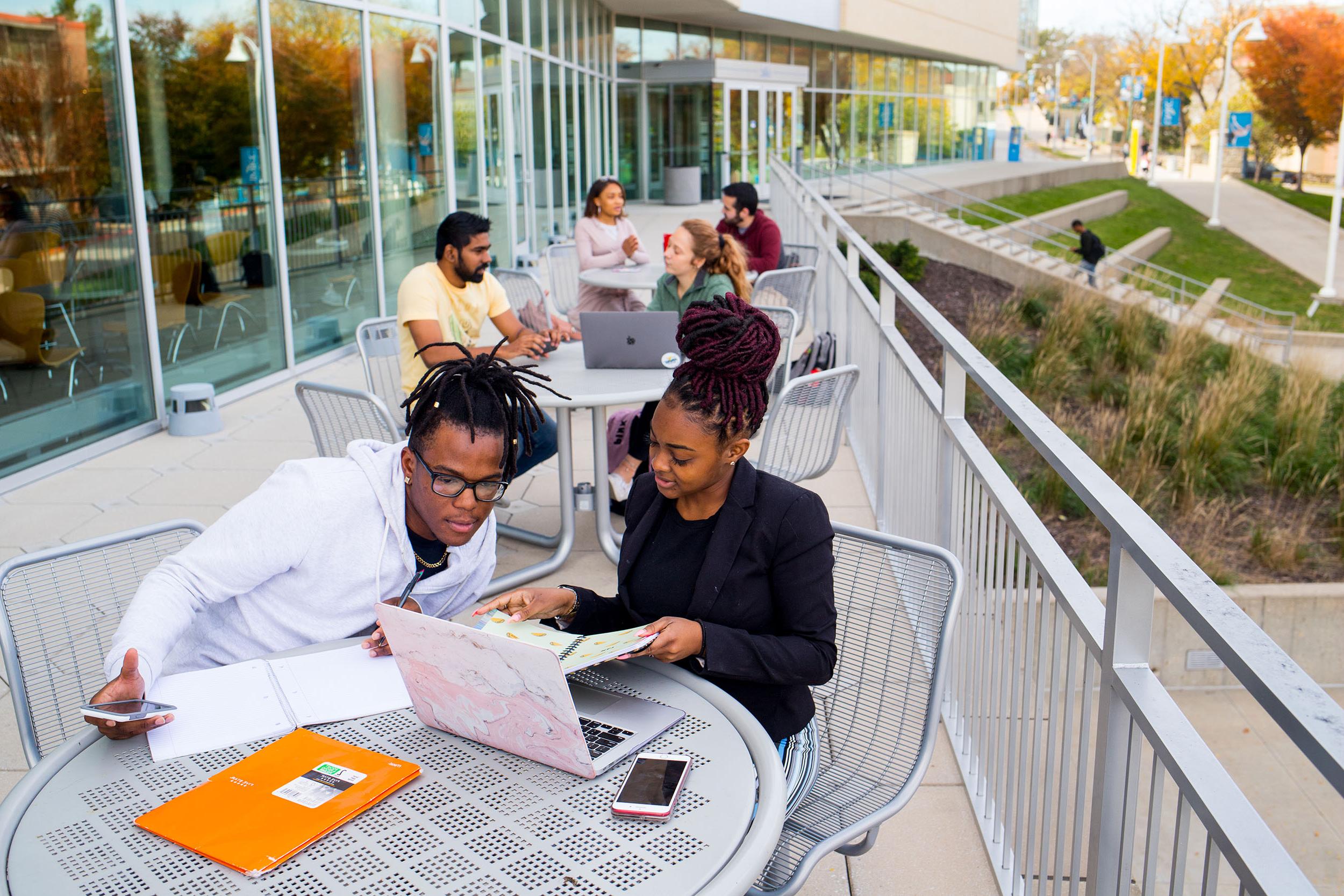 students sit at tables studying on porch of Student Union